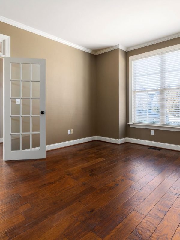 A room devoid of furniture, showcasing hardwood floors and a door, related to flooring services in Austin, TX.