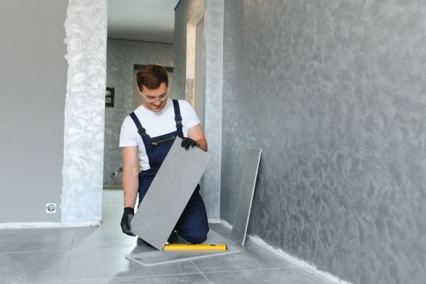 A man carefully places a tile on the floor, representing a tile flooring service in Austin, TX.