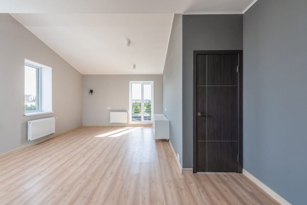 An empty room displaying gray walls and wooden laminate floors, indicative of flooring services in Austin, TX.